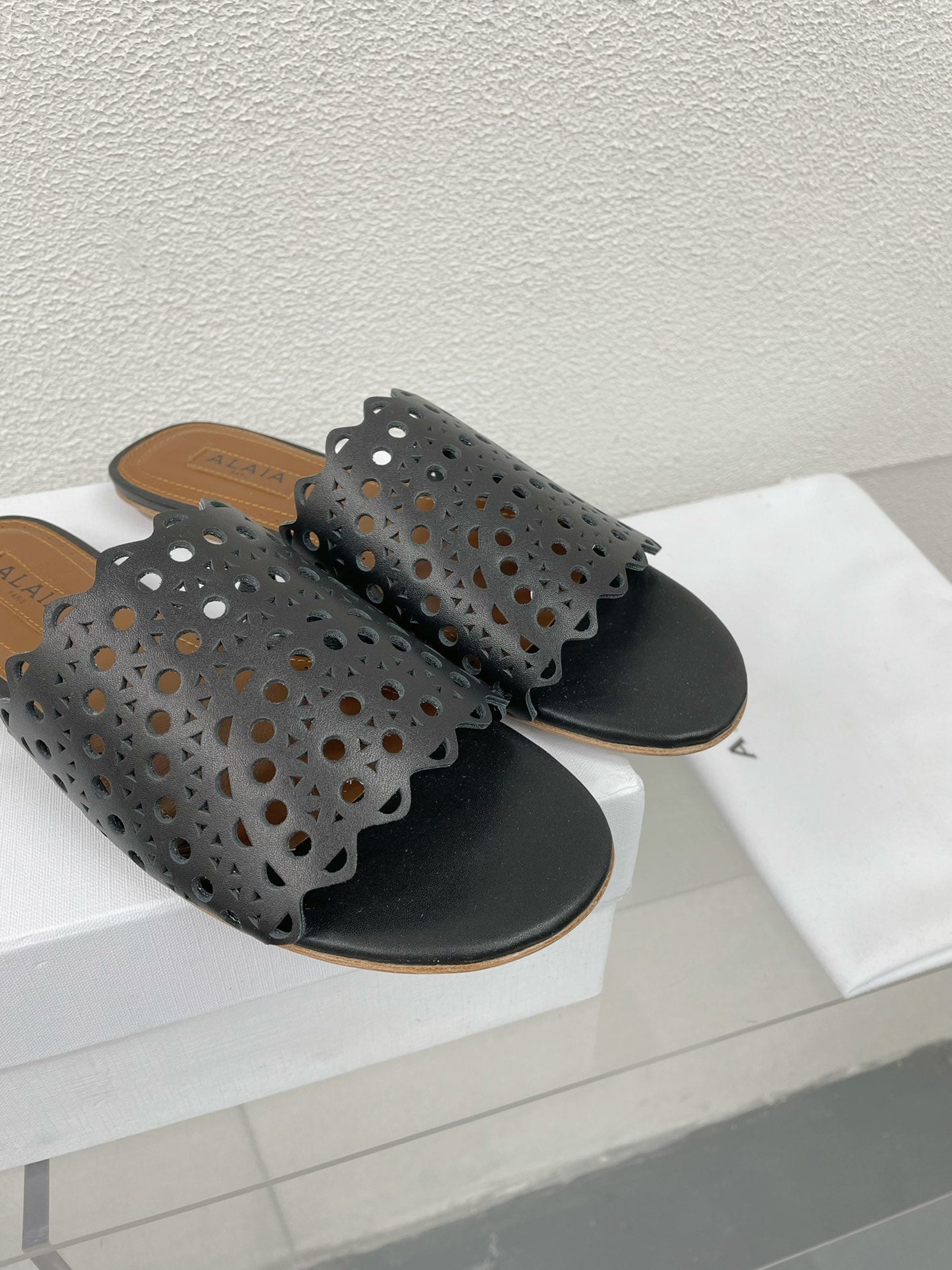 ALAIA VIENNE FLAT MULES IN BLACK LAMBSKIN